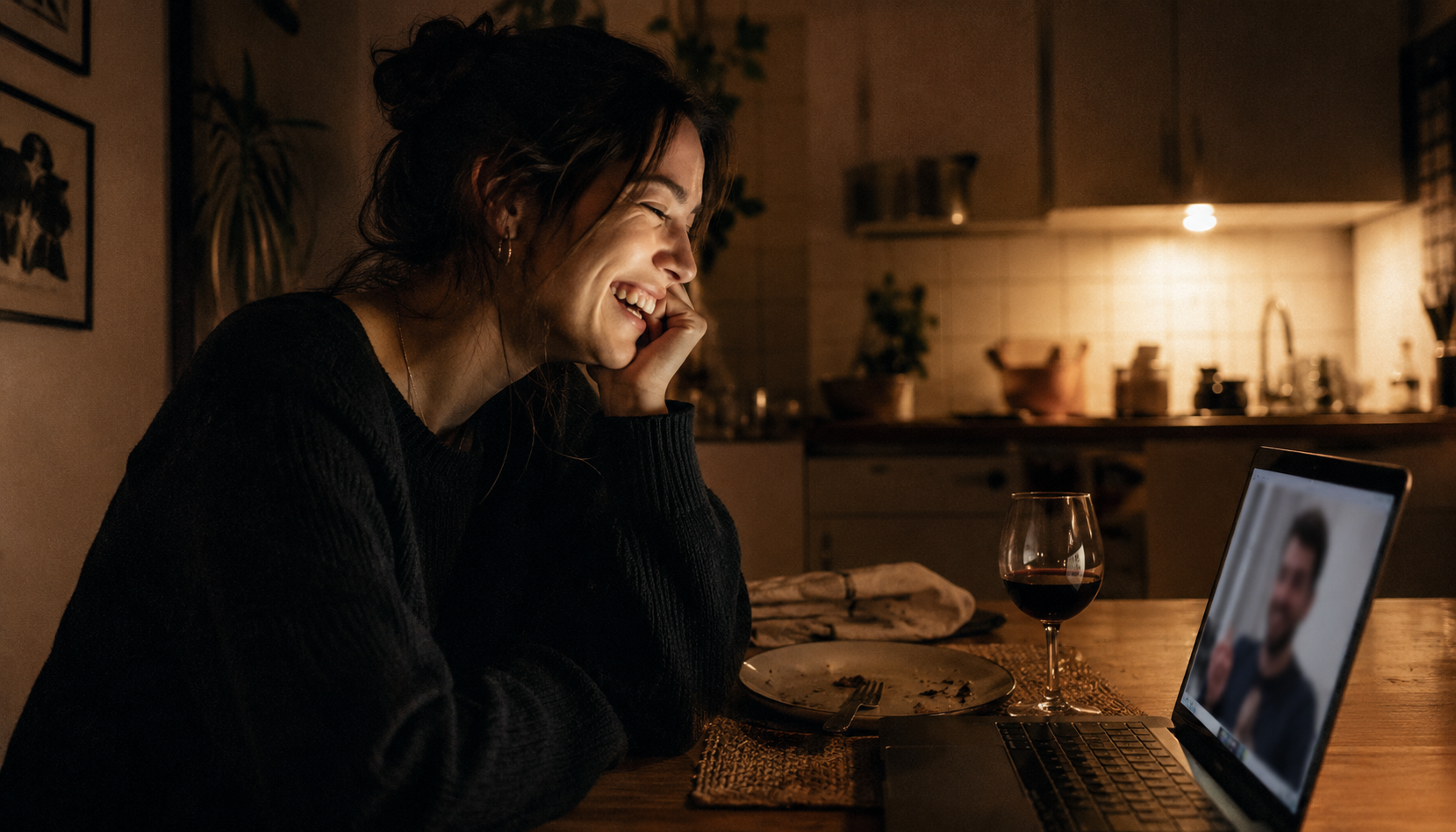 Woman laughing during a video call at her kitchen table in the evening